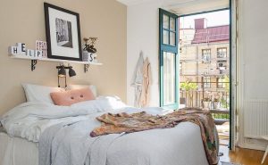 Letto matrimoniale con mensola bianca al posto della testiera su cui sono appoggiati un quadro e dei cubi bianchi con lettere nere