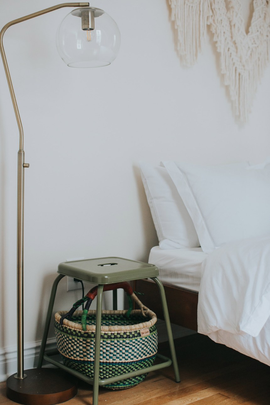 Particolare della camera da letto: comodino fatto con sgabello e cesto più piantana