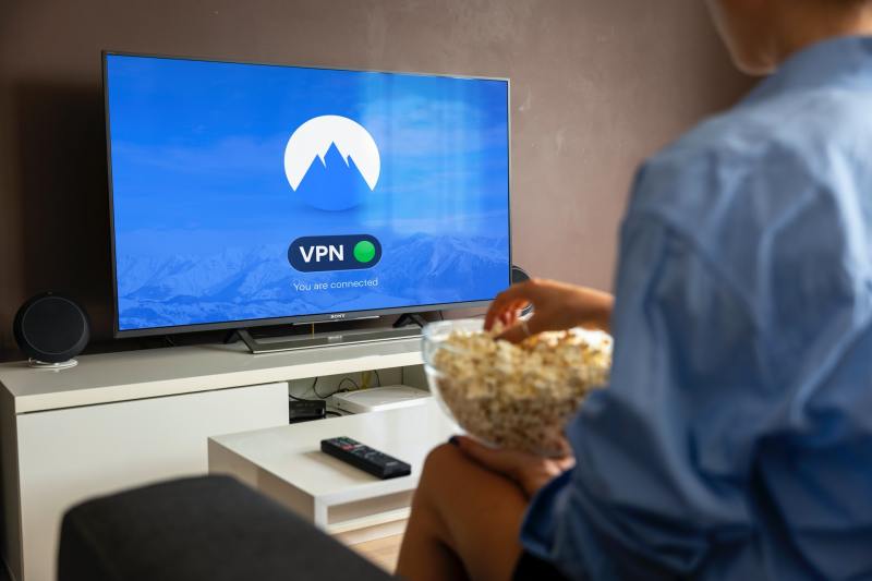Immagine di una persona seduta sul divano con dei pop corn, davanti a una smart TV che avvisa l'avvenuta connessione tramite VPN