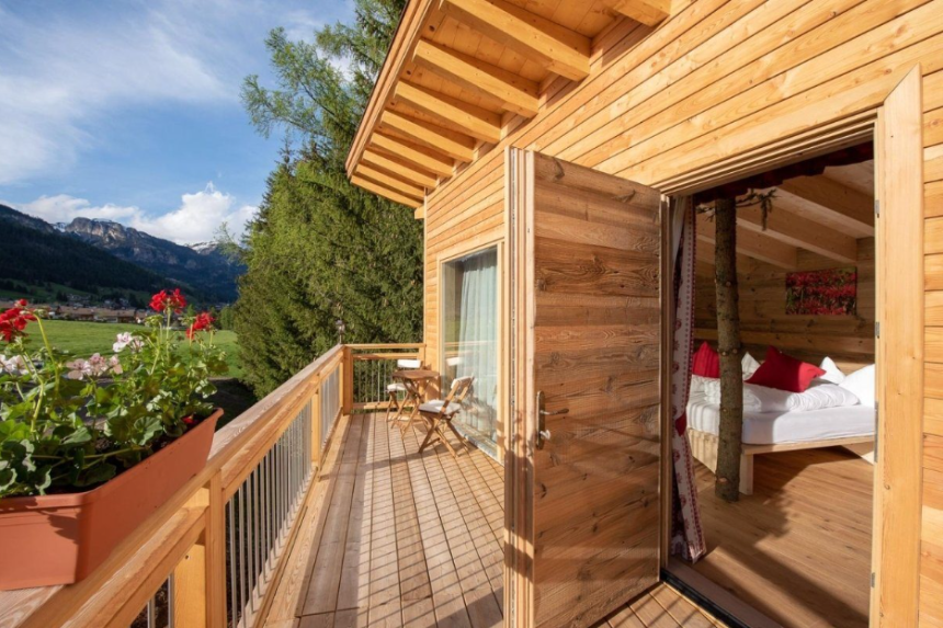 Esterno della casa sull'albero da dove si vede il terrazzino e un pezzetto della camera da letto con albero nel centro della stanza